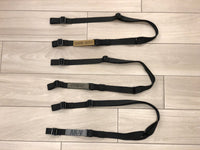 Three black TOIM customizable quick adjust two point slings with custom text engraved on the pull tabs lying on the floor.